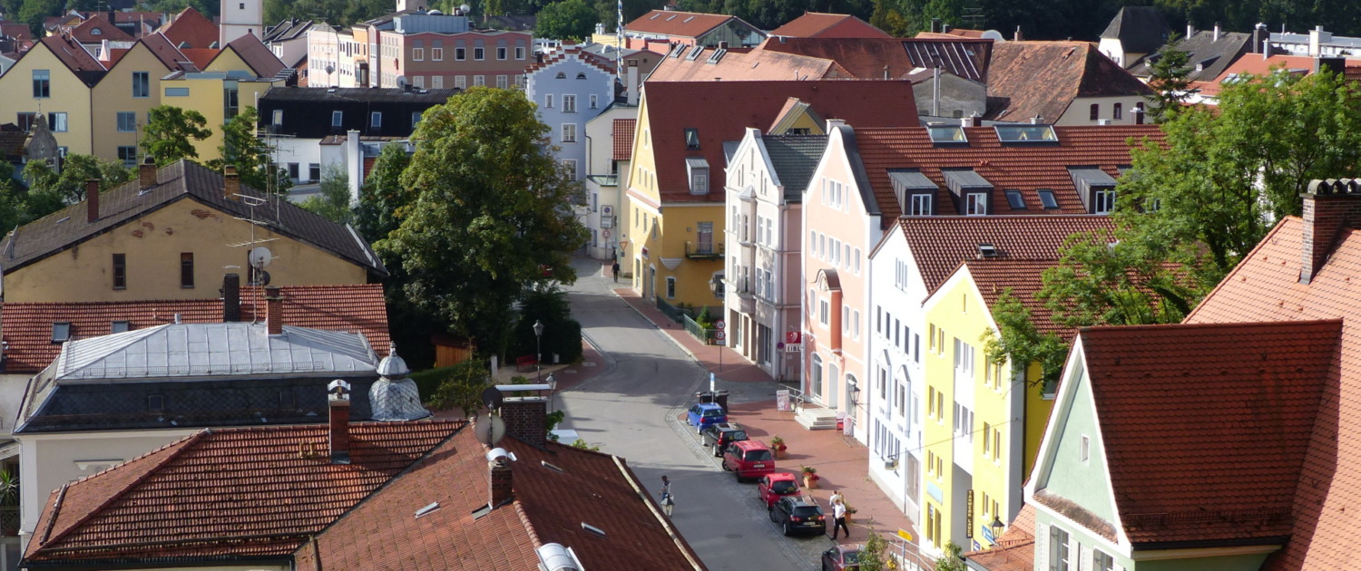 Blick auf eine ruhige Straße mit farbenfrohen Altstadthäusern und roten Ziegeldächern.